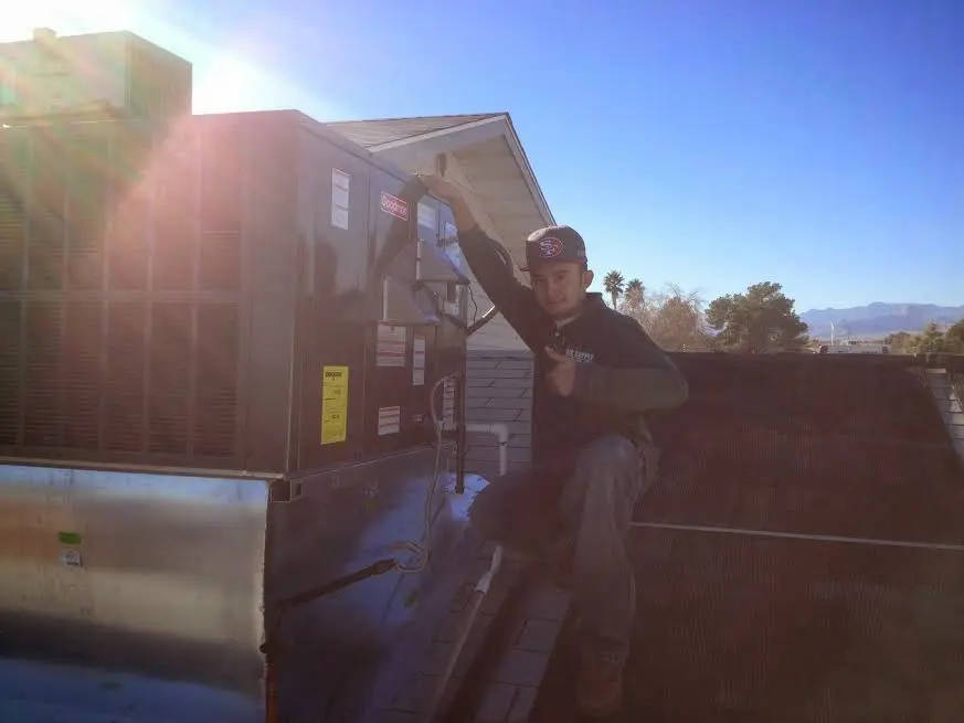 HVAC technician performing Air Duct Cleaning on a rooftop unit in Lemoore